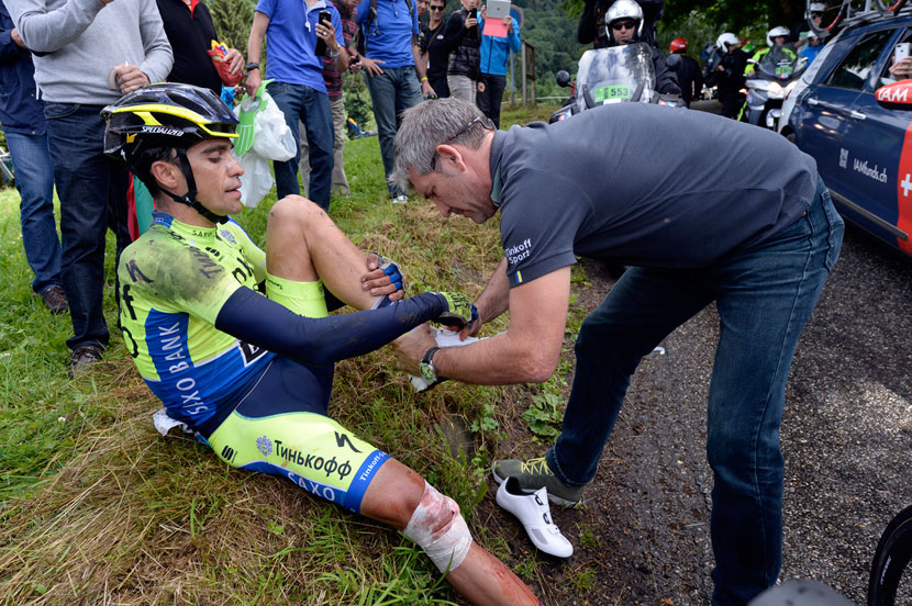 Alberto Contador gets a new set of shoes off his team's mechanic, Faustino Munoz, after being patched up by the Tour's medico... he would ride another four kilometres before quitting the race with a broken tibia. Photo: Graham Watson